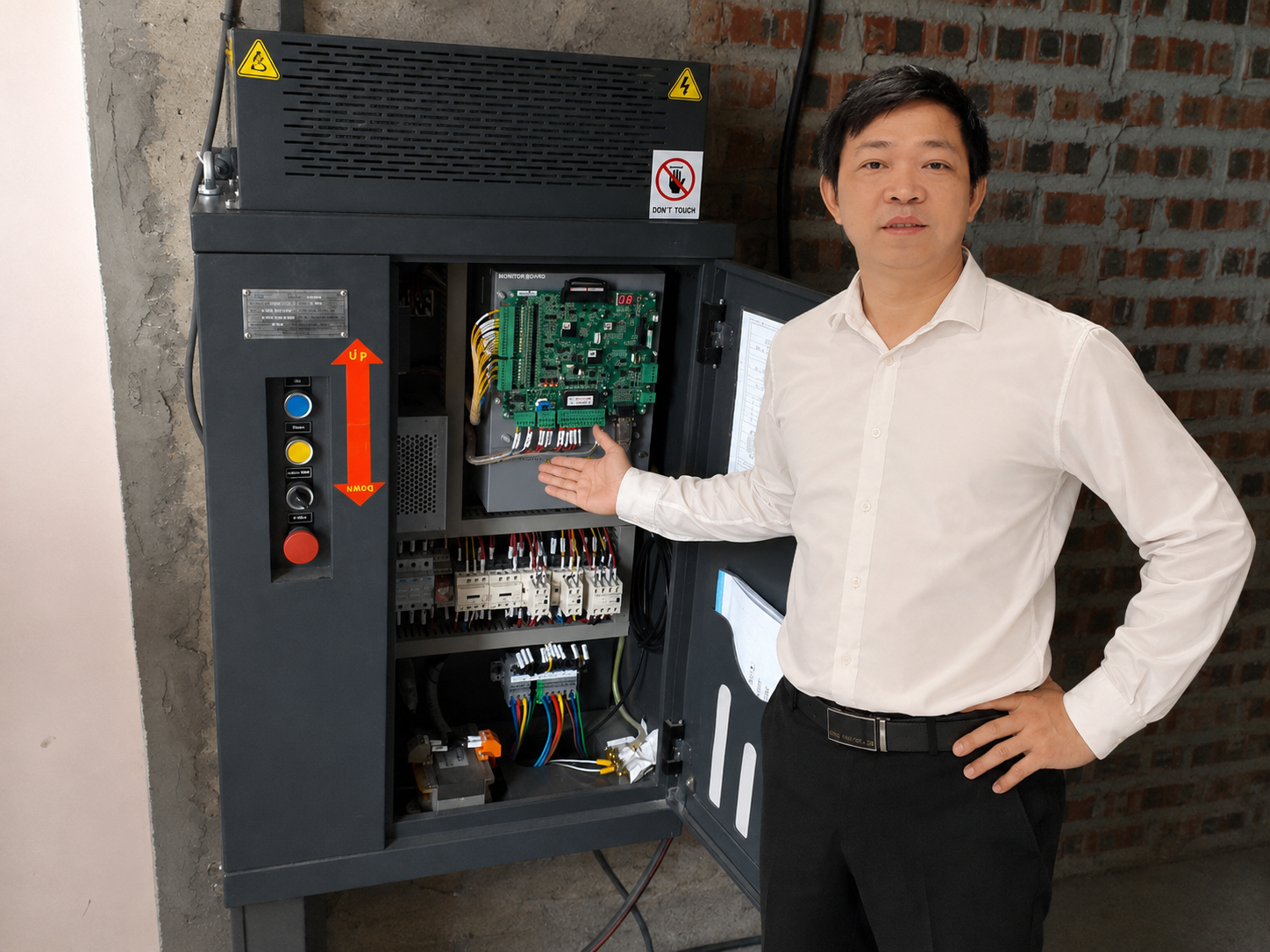 Kỹ sư giới thiệu tủ điều khiển thang máy với bảng mạch và hệ thống nút bấm vận hành